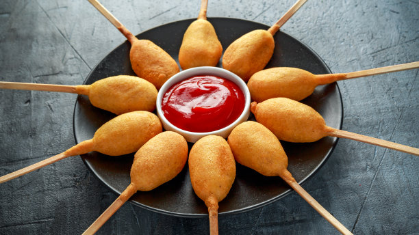 黑色盘子里的迷你玉米热狗配番茄酱图片下载