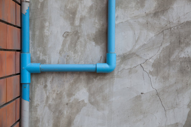 蓝色水管在抛光的混凝土墙上图片下载