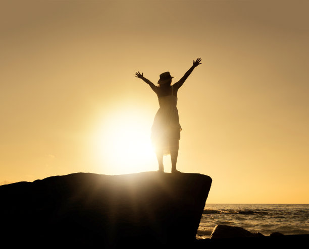 穿着白色连衣裙的亚洲美女剪影正站在悬崖上摆姿势。图片下载