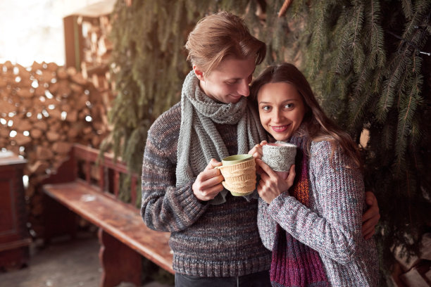 照片的快乐的男人和漂亮的女人与杯子在室外冬天。寒假放假了。圣诞快乐的一对男女喝热饮。夫妇在爱图片下载