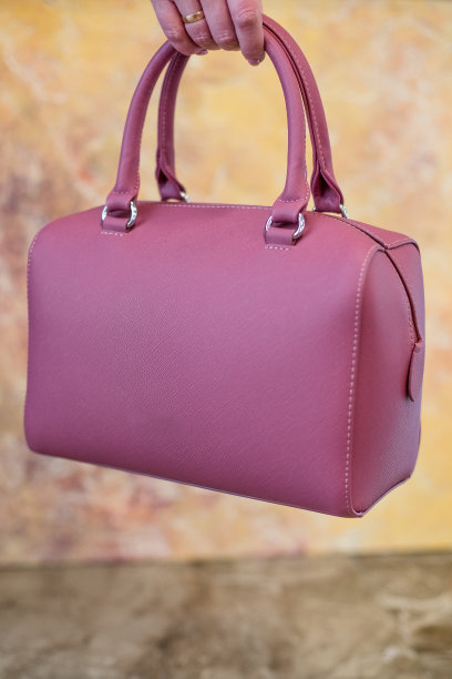 手拿粉色女士手提包，女士包，粉色女性手包，粉色手包。女人的包孤立在大理石背景。豪华美丽的粉红色皮革女包图片下载