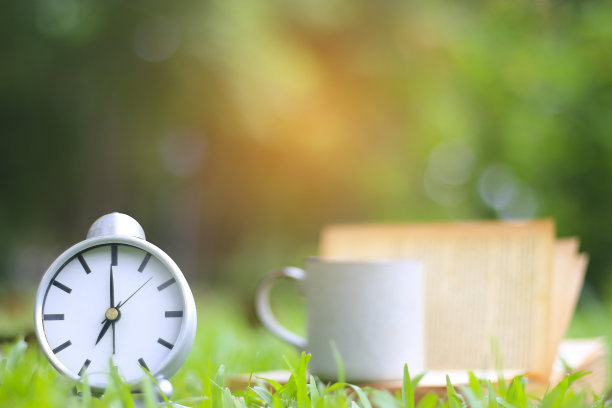 股票的照片: 在绿色的草地上，喝着咖啡，放着时钟和书图片下载