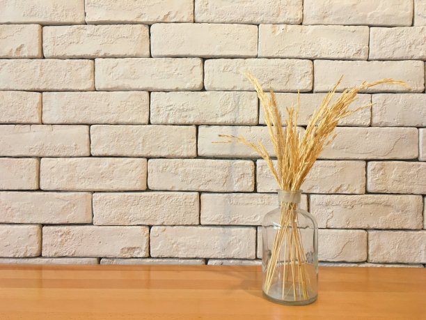 干草装在一个透明的玻璃瓶里，放在砖墙的木桌上图片下载