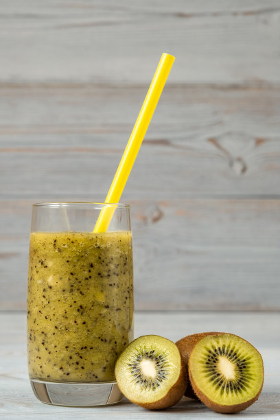 绿色的猕猴桃冰沙在玻璃杯和猕猴桃片在灰色的背景图片下载