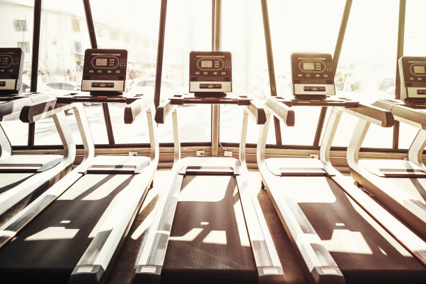健身和健康的背景理念。早晨在阳光下清空健身房的跑步机。图片用于添加文字信息。设计艺术作品的背景。图片下载