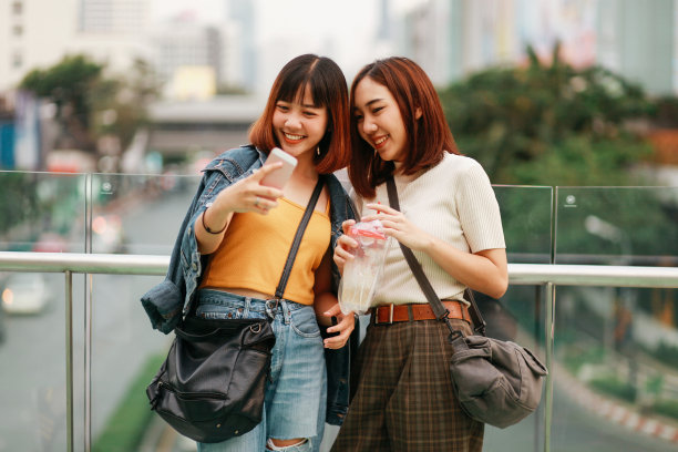 年轻的亚洲女性一起在曼谷购物，用手机自拍图片下载