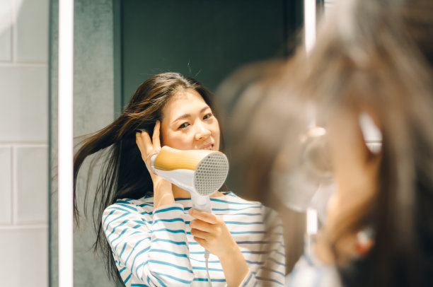 年轻女子在晾干她的头发。图片下载