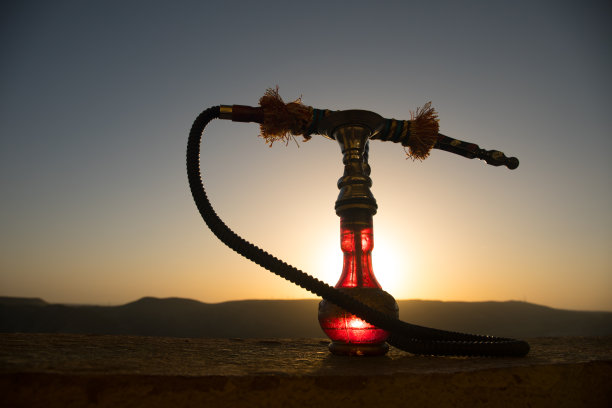 水烟，传统阿拉伯水管，直接日落光，户外照片。山的背景或水烟的剪影在日落的背景。户外。图片下载