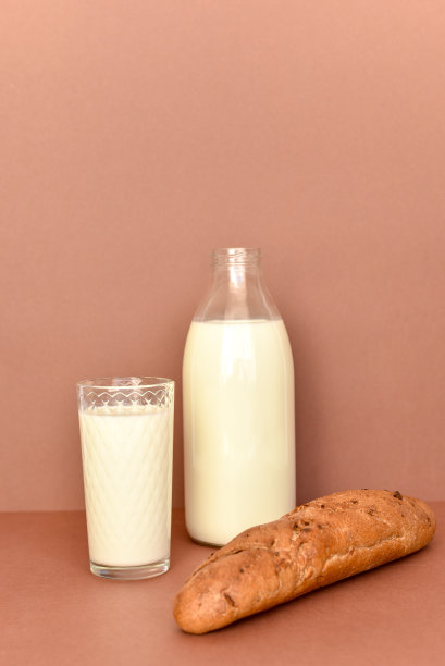 牛奶在透明的玻璃瓶和玻璃和面包图片下载
