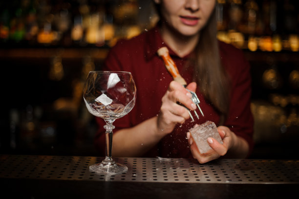女酒保正在准备一块冰块，准备制作Aperol注射器鸡尾酒图片下载