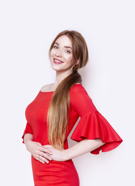 漂亮的年轻女子穿着时尚优雅的红色连衣裙，手放在臀部，画室肖像快乐的微笑图片下载