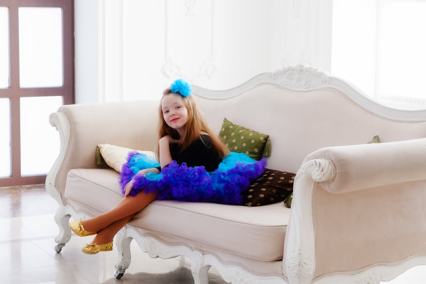 那个穿着蓝色裙子的女孩坐在沙发上微笑着图片下载