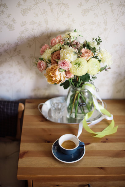 在质朴的木桌上，用蓝色瓷杯盛着美味新鲜的浓咖啡，还有盛开的康乃馨、毛茛、玫瑰花束图片下载