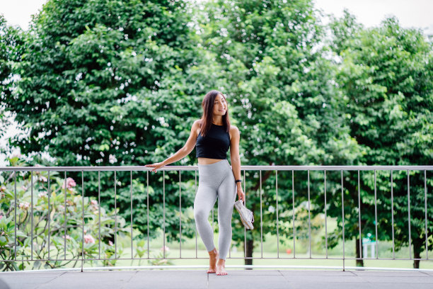 一个年轻的，漂亮的新加坡华人少年倚靠在栏杆上的照片。图片下载