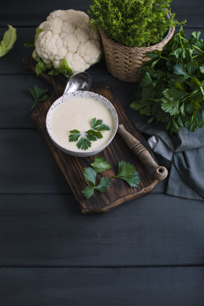 奶油花椰菜汤，奶油和蔬菜，在一个白色的杯子，在木板和黑色的背景。复古的照片。新鲜蔬菜和花椰菜。本空间图片下载