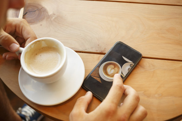 学生使用触摸屏智能手机，一边喝咖啡一边上网。图片下载