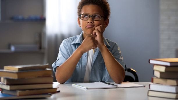 一个非洲男孩想着学校的作业，在做作业时感到无聊图片下载