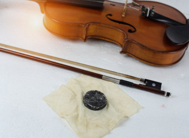 在小提琴用松香选择性聚焦时，放在弓旁，模糊的灯光设计背景。图片下载
