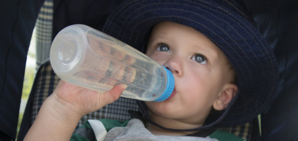 蹒跚学步的孩子手持奶瓶素材图片