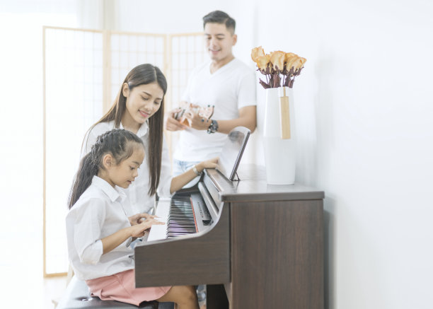 亚洲家庭，母亲和女儿弹钢琴，父亲在家里的家庭乐队演奏吉他，家庭关系的概念图片下载