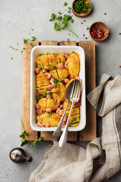 灰白色背景下，烤土豆配火腿、香草和面包屑。北欧美食。前视图。图片下载