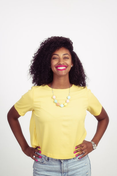 美丽的卷发女人与手在臀部摆姿势。图片下载