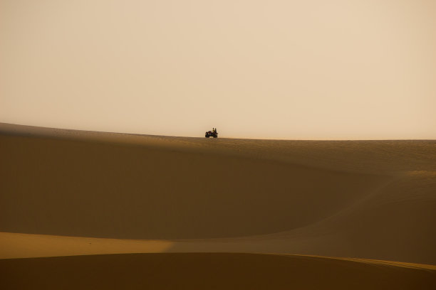 在日出的沙丘上骑四轮摩托车图片下载