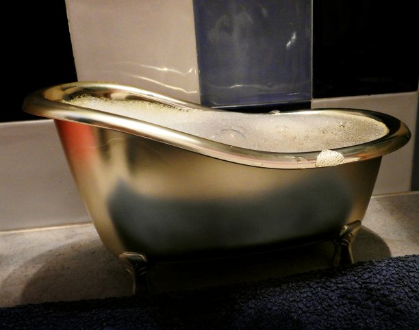 一个装满水和肥皂的浴缸，上面铺着蓝色的地毯图片下载