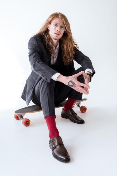 一头卷发的时髦商人坐在滑板上图片下载