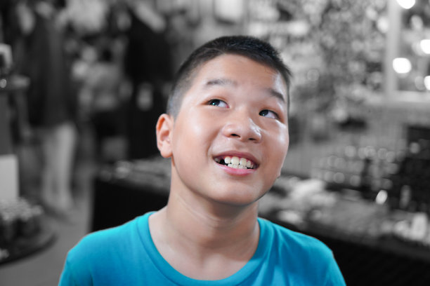 肖像亚洲男孩:近距离男孩。他有一个小眼睛和有趣的微笑。在黑白背景上。图片下载
