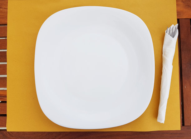 顶视图的空白色盘子，白色的盘子与餐巾设置在桌子上的餐厅户外。图片下载