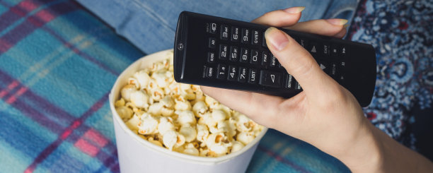 女孩在客厅里看电视，吃着爆米花。懒惰的概念图片下载