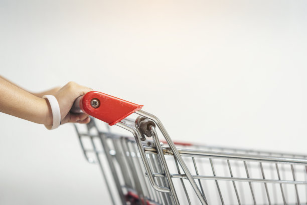 一个亚洲女人的手拿着一个空的购物车。这张图片是软焦点。图片下载