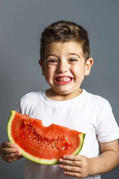 有趣的孩子在室内吃西瓜。健康的食物图片下载
