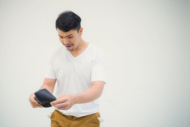 一个没有钱的人可怜的姿势站在白色的背景上显示他的空口袋图片下载