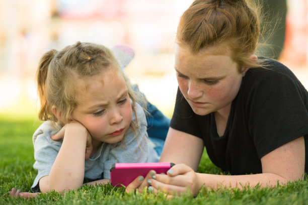 孩子们在草坪上看手机视频图片下载