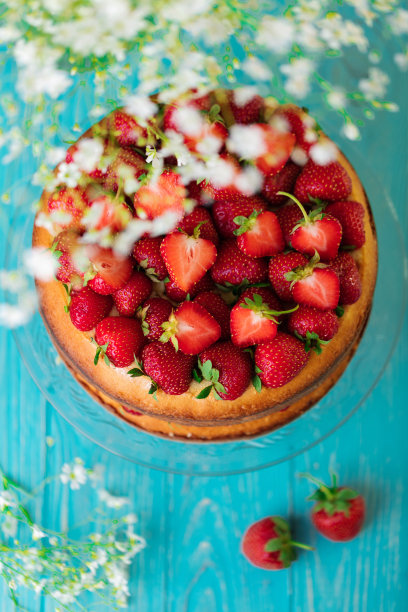 蓝色背景上的玻璃架子上自制的草莓蛋糕。图片下载