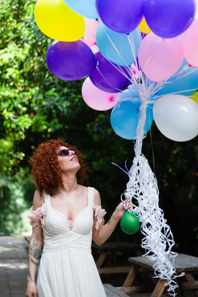 红发美丽的新娘，卷着头发，放飞五颜六色的气球图片下载