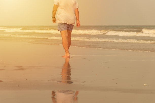 一个人独自走在海滩上。海滩旅游在夏季时间概念图片下载