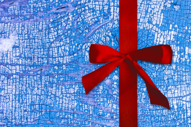 红色的缎带。底色为蓝色，旧板上油漆开裂的纹理素材图片