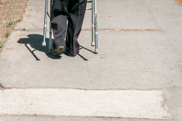 年老的残疾妇女独自行走和沮丧的街道在城市的可调节拐杖或手杖帮助图片下载