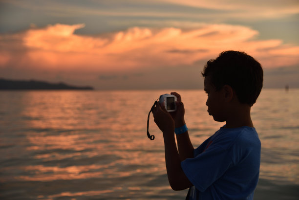 菲律宾长滩岛，一个小男孩在美丽的白色沙滩上拍下了一张日落的照片。图片下载