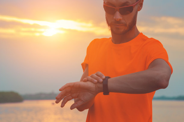 在户外运动/慢跑后查看时间。光学聚焦在手和手表上。图片下载