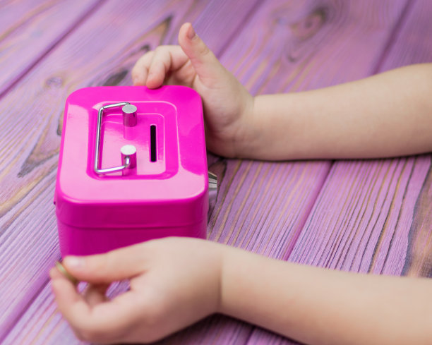 一个小孩的手和一个存钱罐。图片下载