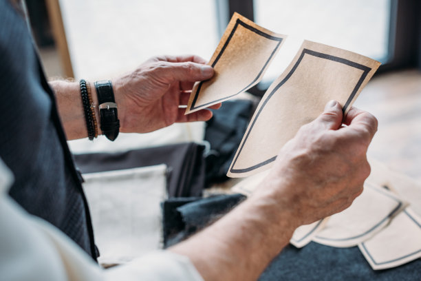 裁剪的裁缝拿着纸口袋图案的照片，以推迟它在缝纫车间的布料上图片下载