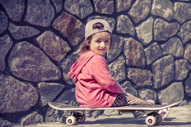 一个时尚的小女孩正拿着滑板在外面玩，那是一个孩子的美好情感。图片下载