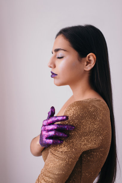 工作室肖像美丽的黝黑的年轻女子与闪亮的紫色闪光在嘴唇和手图片下载