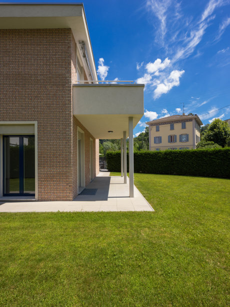 在阳光明媚的日子里，房子的外部有绿色花园图片下载