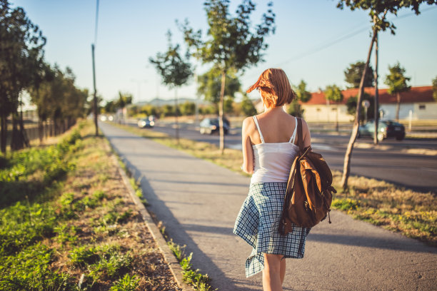女子背着背包在阳光明媚的日子里散步和放松图片下载