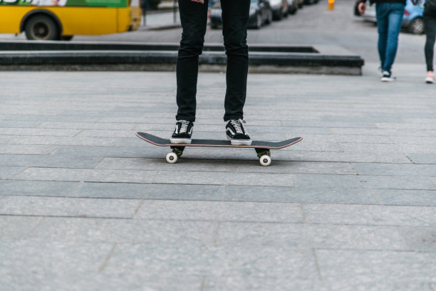 小男孩把腿凑拢来玩滑板。城市运动图片下载